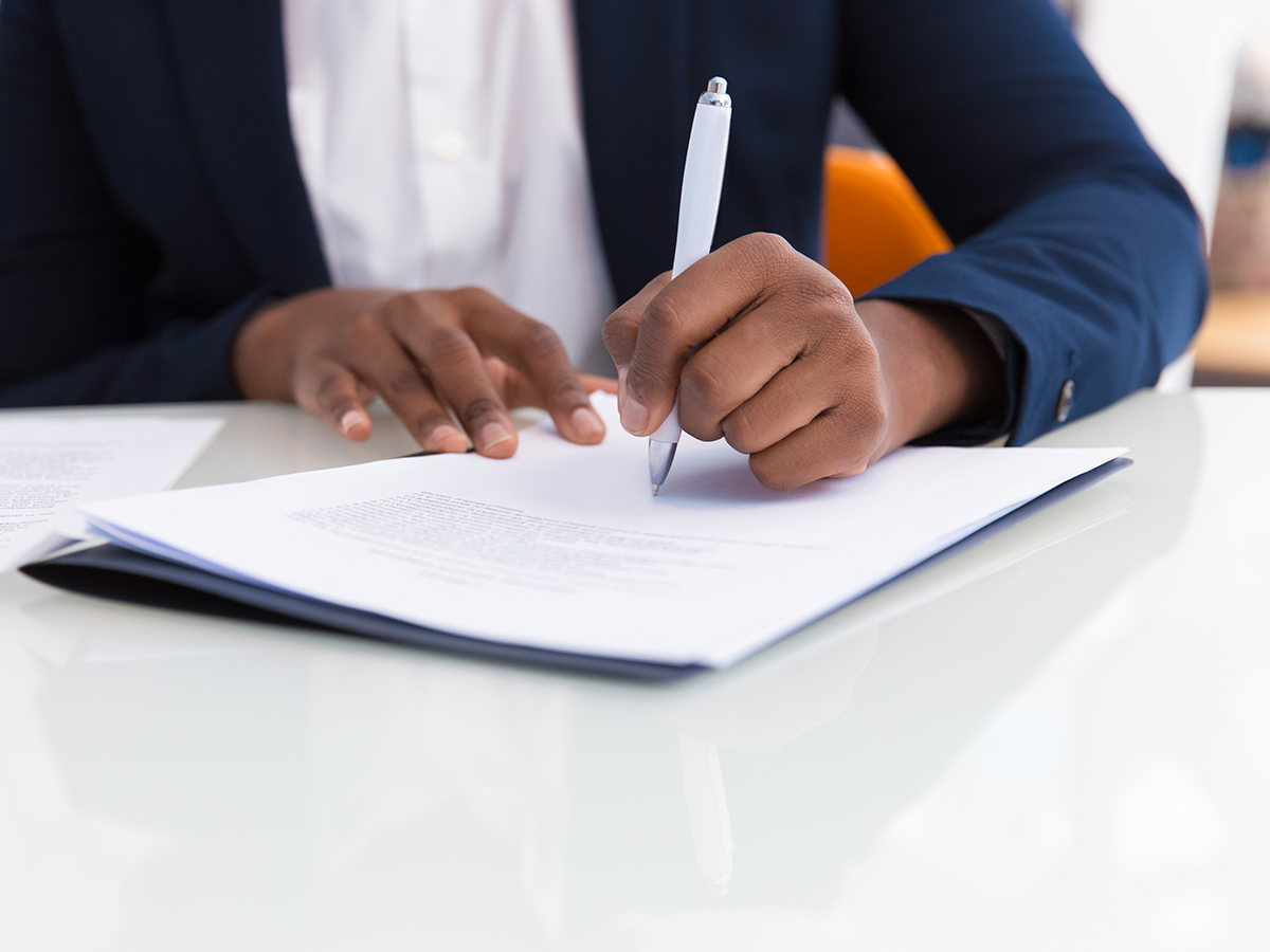 Paralegal Seated at Desk Taking Notes During Meeting